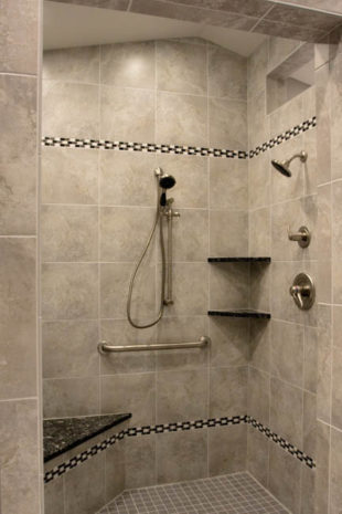 Tiled bathroom shower with double soap shelves and hand shower